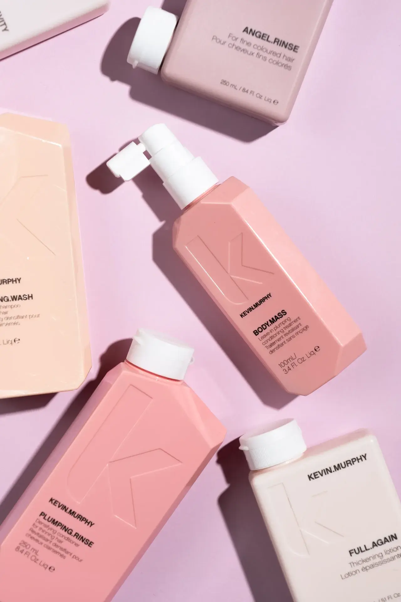 Vibrant flat-lay of pink Kevin Murphy hair care products scattered on a pastel pink background
